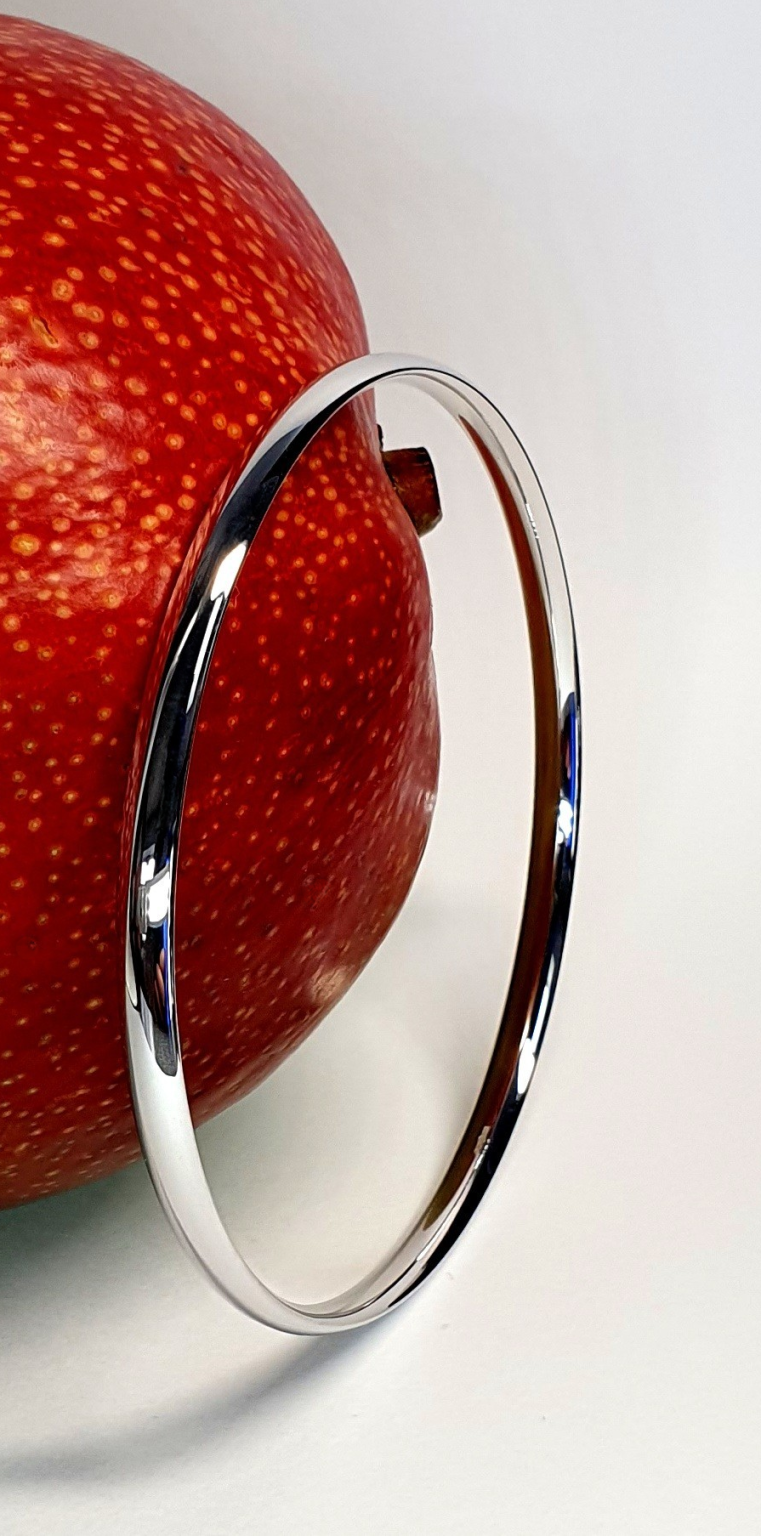 9ct white gold court shape bangle pictured with a mango.