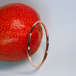 Pink gold court shape bangle pictured with a mango.