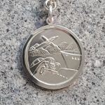 "Reverse side of the Saint Christopher keyring, showcasing embossed travel symbols including a car, ship, and aeroplane, highlighting its craftsmanship and design."