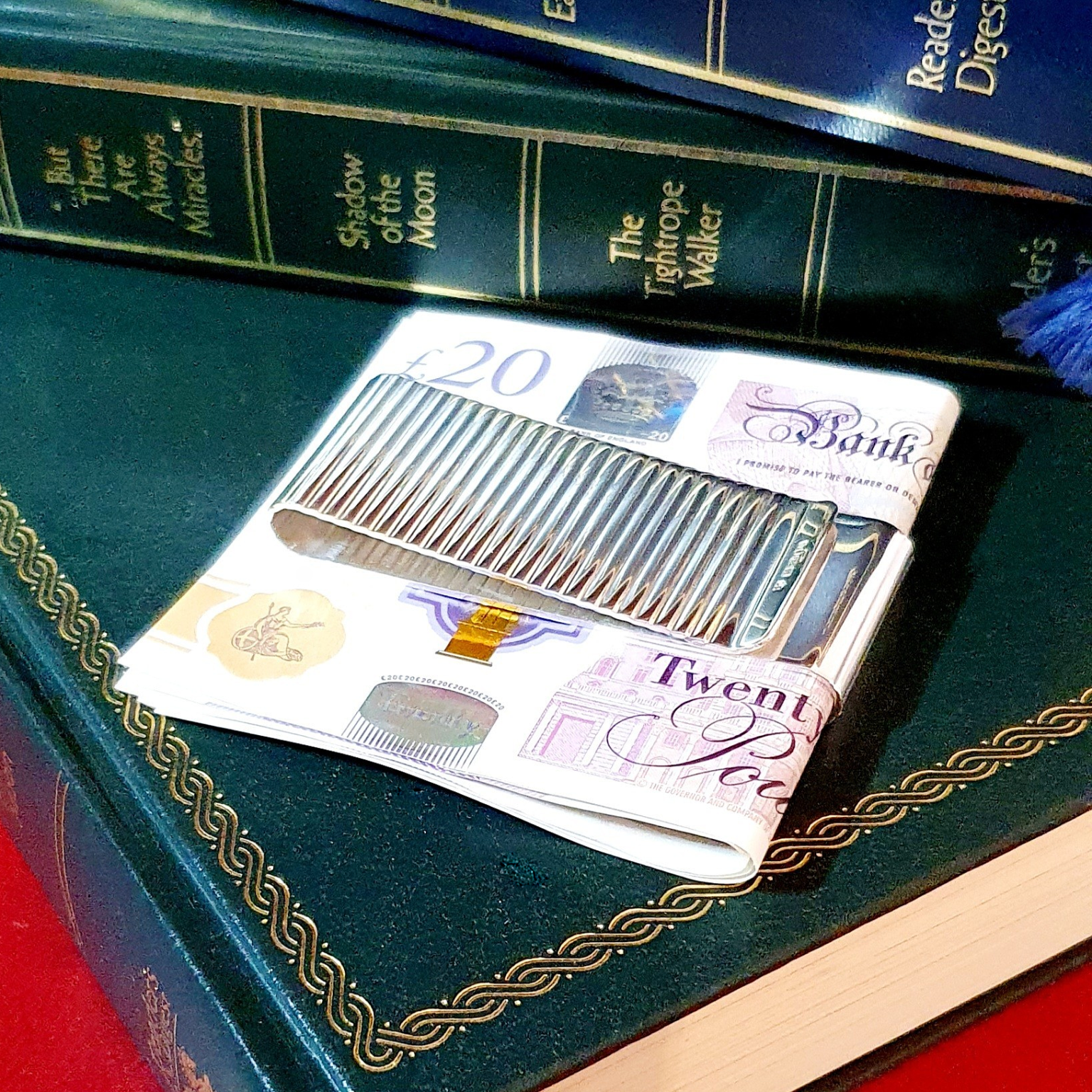 Washboard design, silver, two-sided cash clip pictured on green books with twenty pound notes.