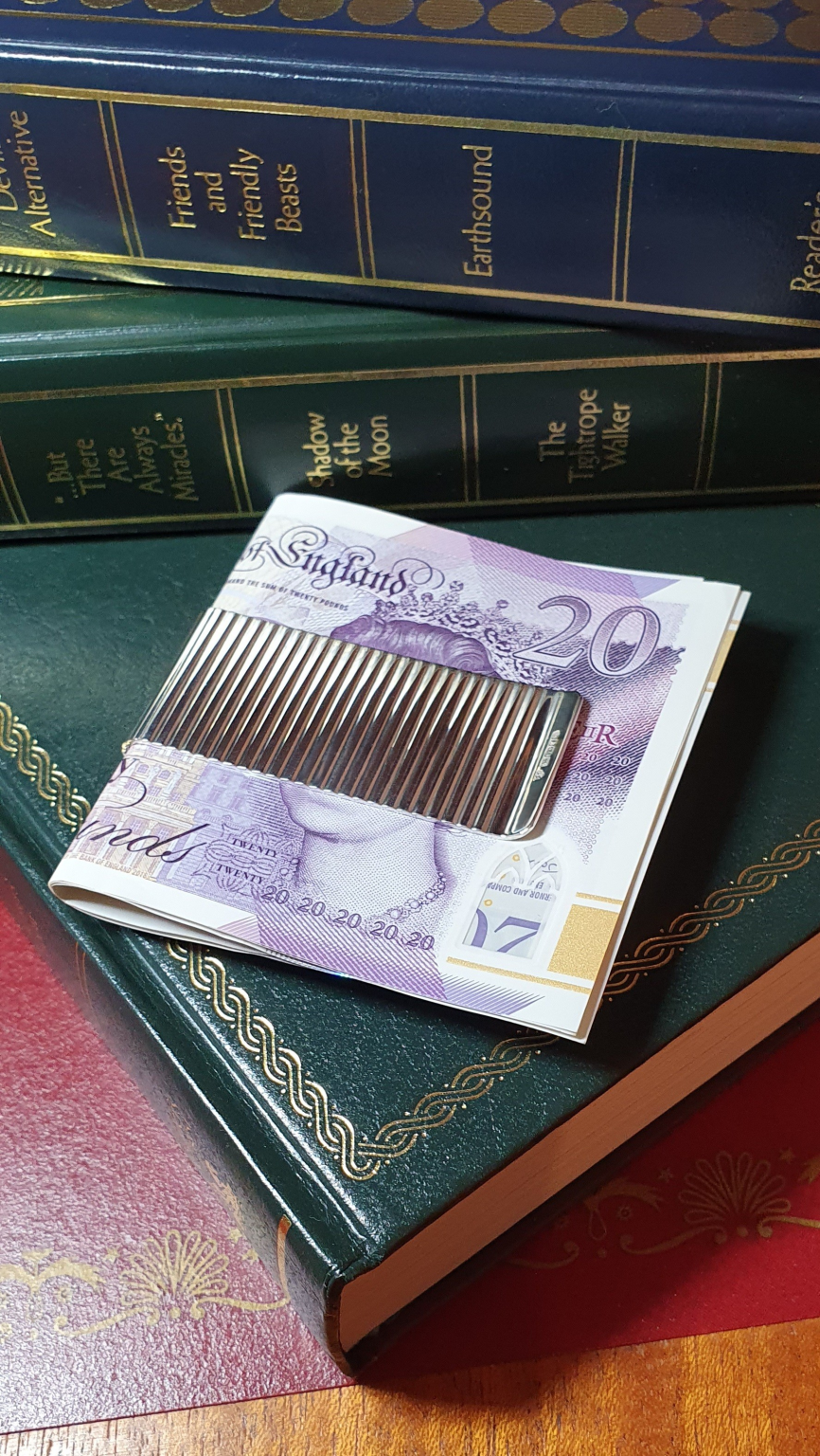 Washboard design, sterling silver, two-sided cash clip pictured on green books with twenty pound notes.