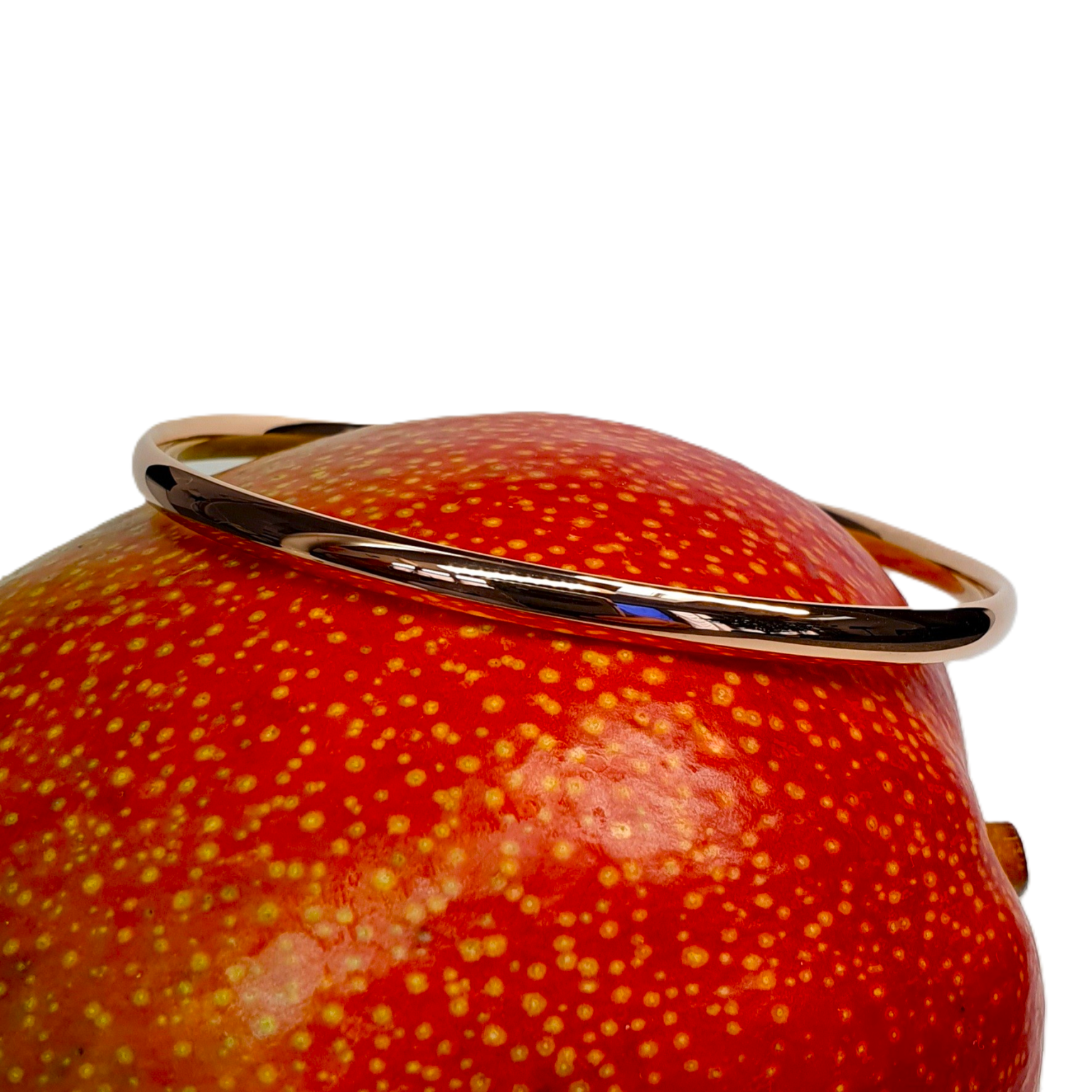 Red gold court shape bangle pictured on a mango.