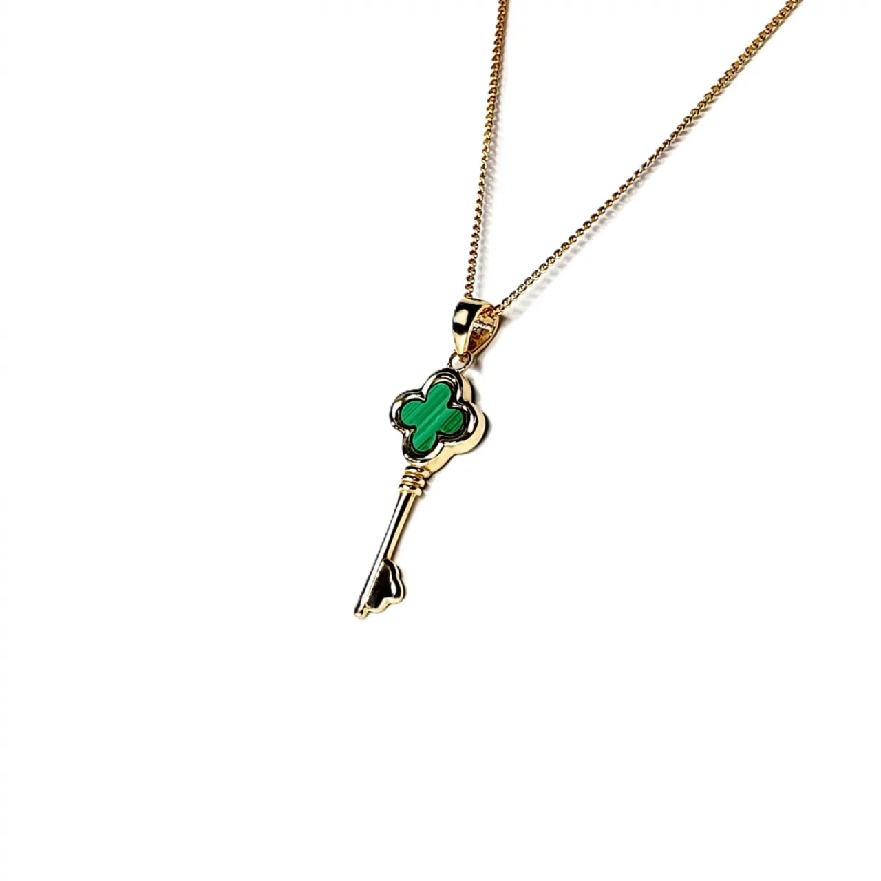 Side view of the 9ct gold malachite key necklace angled to the left, showing the depth of the pendant and the curvature of its key handle.