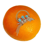 Blue Zircon gold brooch pictured on an orange.