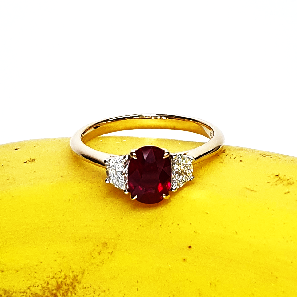 An 18ct yellow gold oval ruby and two half-moon diamond ring with white gold settings on the diamonds is pictured on a banana, for contrast RA00698.