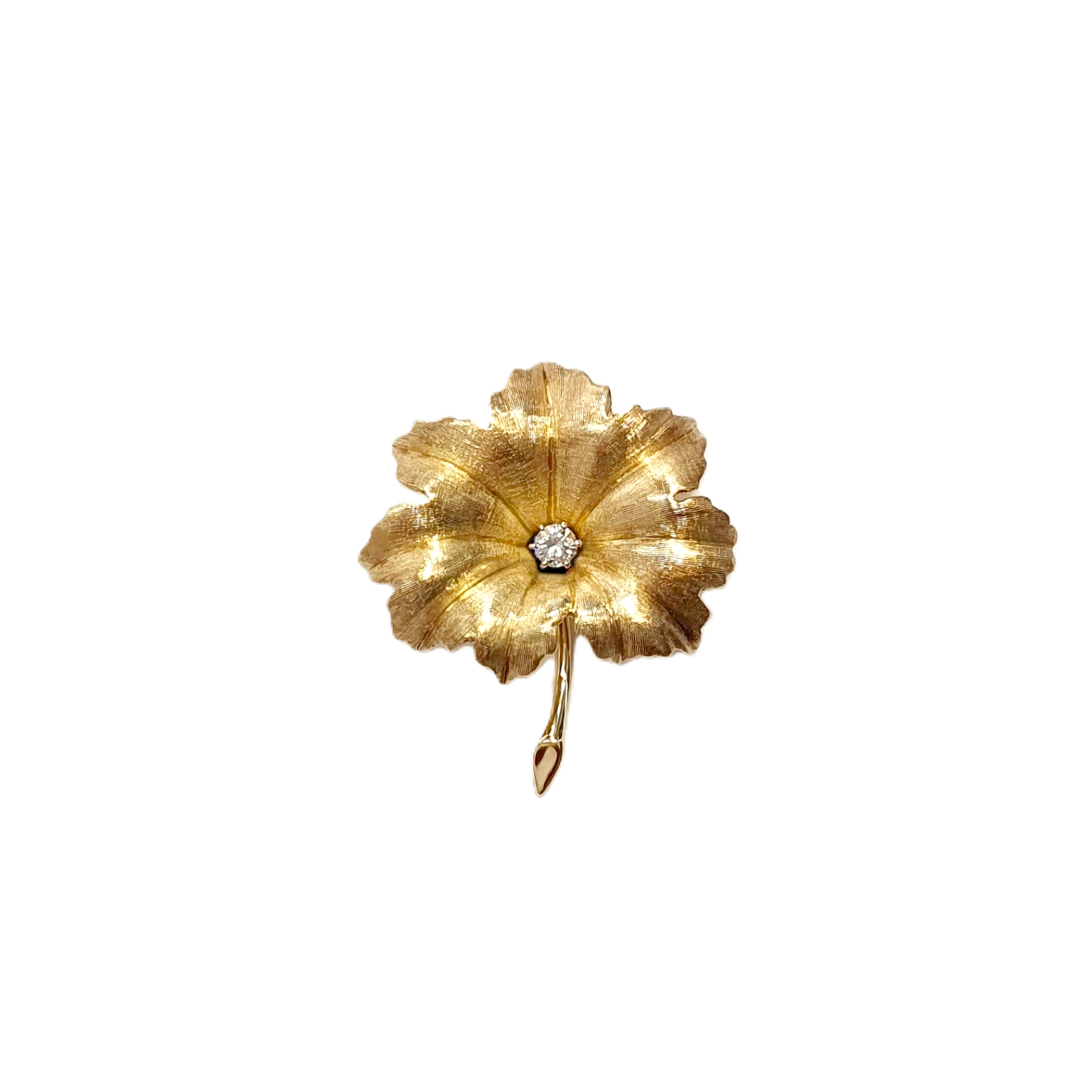 Textured yellow gold leaf brooch pin set with a single sparkling white diamond to the centre.