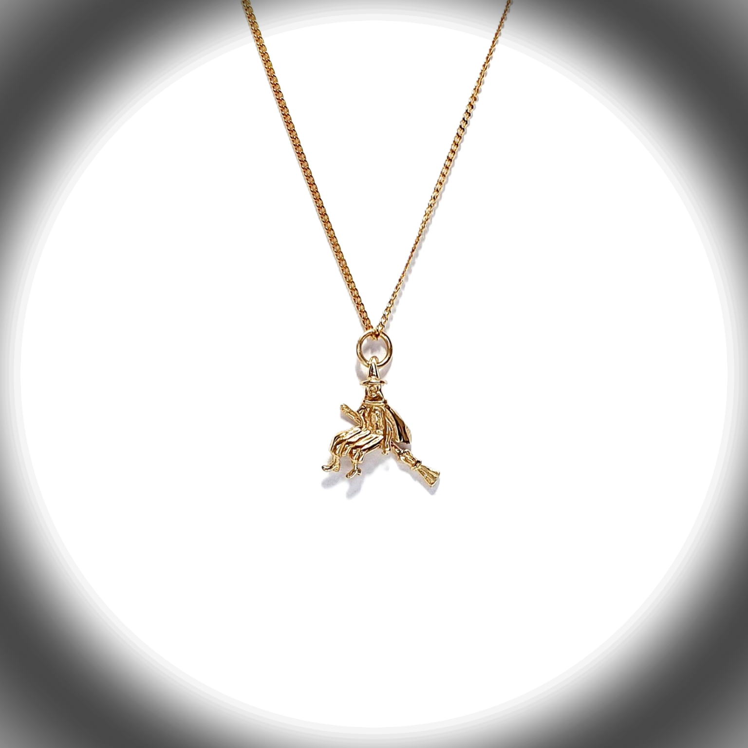 The golden witch is flying past the moon on her broomstick.