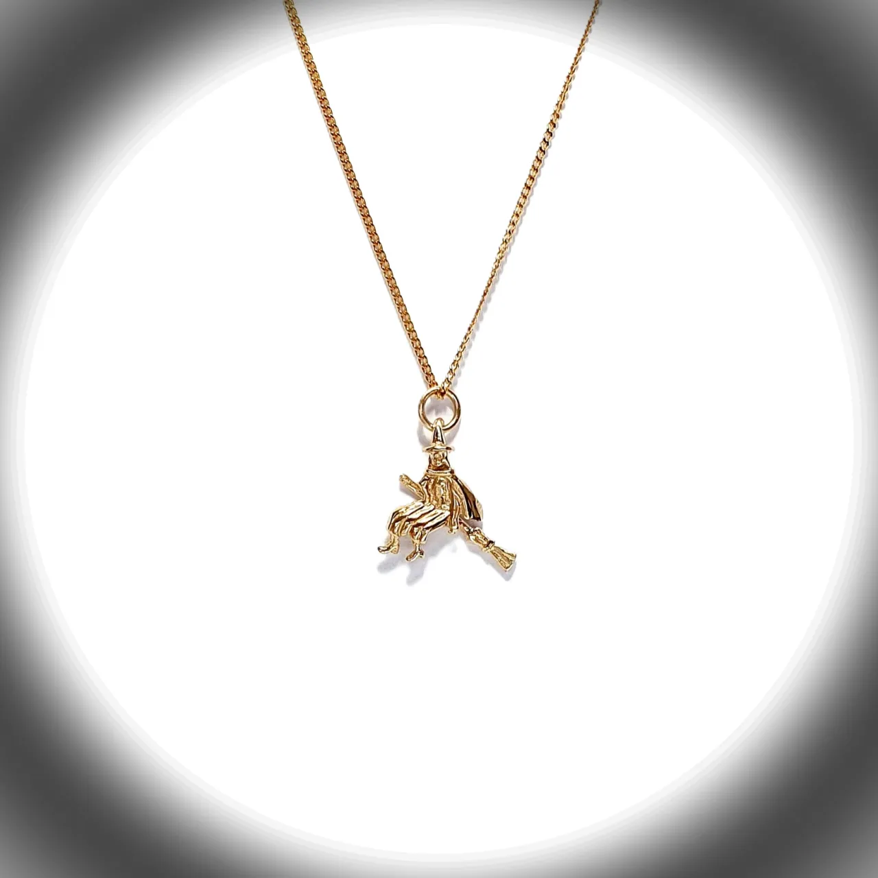 The golden witch is flying past the moon on her broomstick.