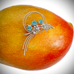Blue Zircon gold brooch pictured on a mango. Pictured close up.