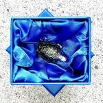 Angled view of the brooch resting in its signature bright blue silk-lined gift box, showcasing premium presentation and packaging.