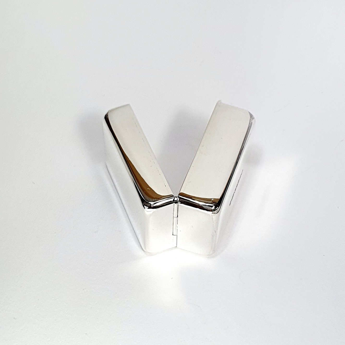 925 silver pill box laying sideways to showcase discreet hinge design and smooth edges in softly lit studio setting.
