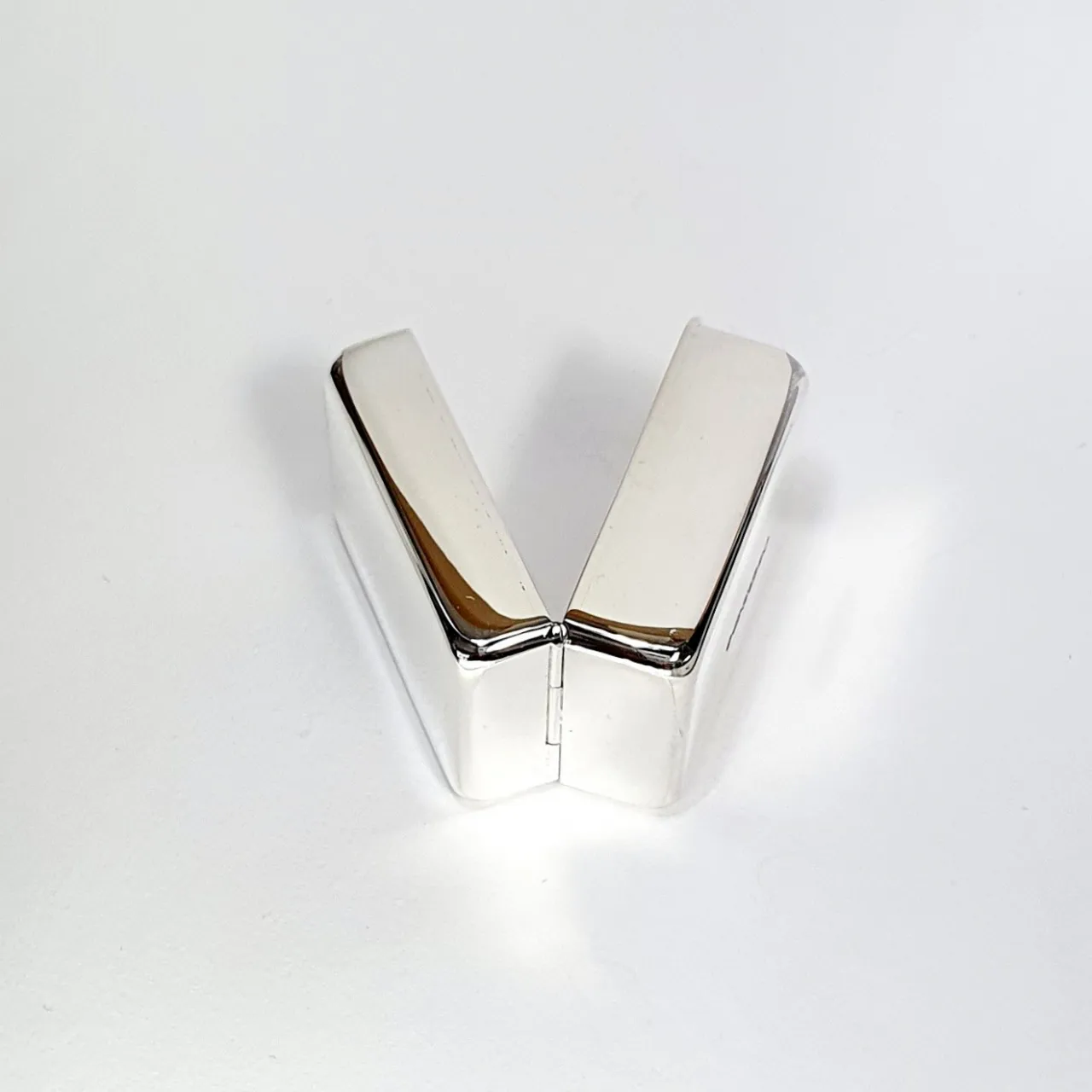 925 silver pill box laying sideways to showcase discreet hinge design and smooth edges in softly lit studio setting.