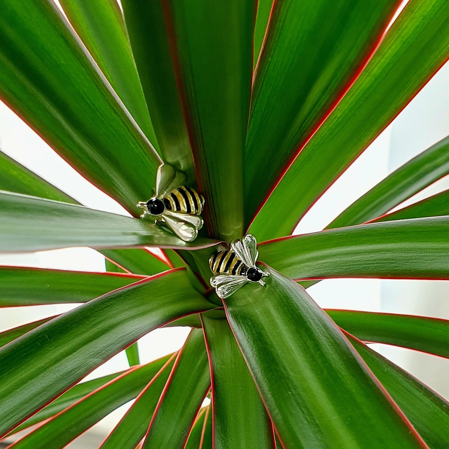 Elegant sterling silver bee cufflinks on green leaves – A refined accessory paired with organic elements to enhance visual appeal.