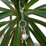 Genuine hallmarked silver tabby cat keyring fob or handbag charm with a grey brown life-like enamelled finish KF00048.Pictuired hanging from a plant.