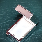 Open hallmarked sterling pill box, tablet shape design with inner compartment visible and matte silver surface captured clearly on green leather back ground.