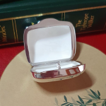 Detailed close-up of pill box interior with bamboo placemat texture beneath Fine matte texture inside the open box captured from above with soft focus on the green bamboo motif underneath.