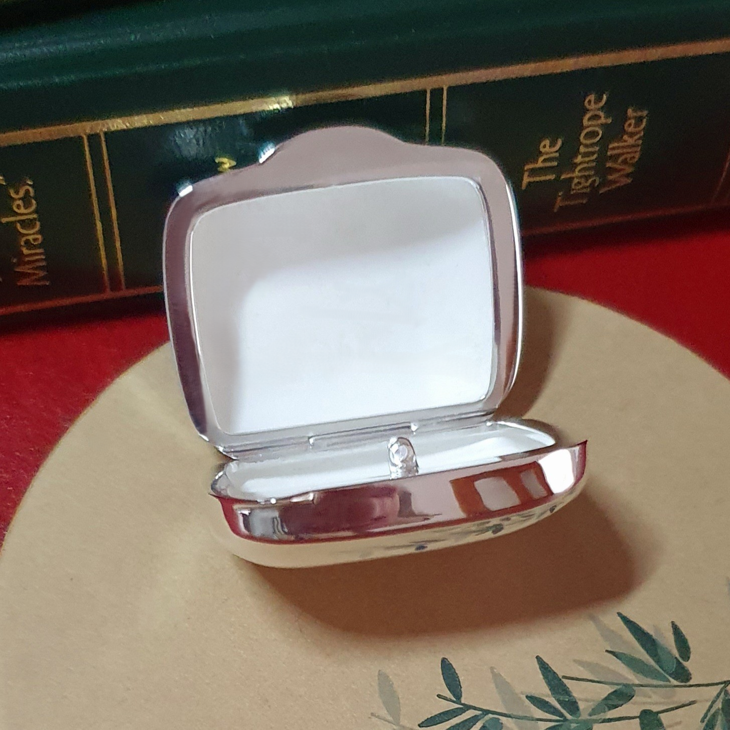 Detailed close-up of pill box interior with bamboo placemat texture beneath Fine matte texture inside the open box captured from above with soft focus on the green bamboo motif underneath.