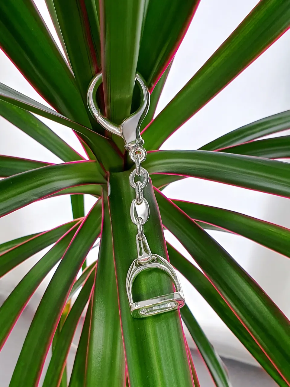 Hallmarked stirrup key fob with a highly polished finish. Pictured hanging from a plant for contrast.