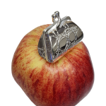 Purse-inspired pill box displayed atop red apple to show compact scale and shine.
