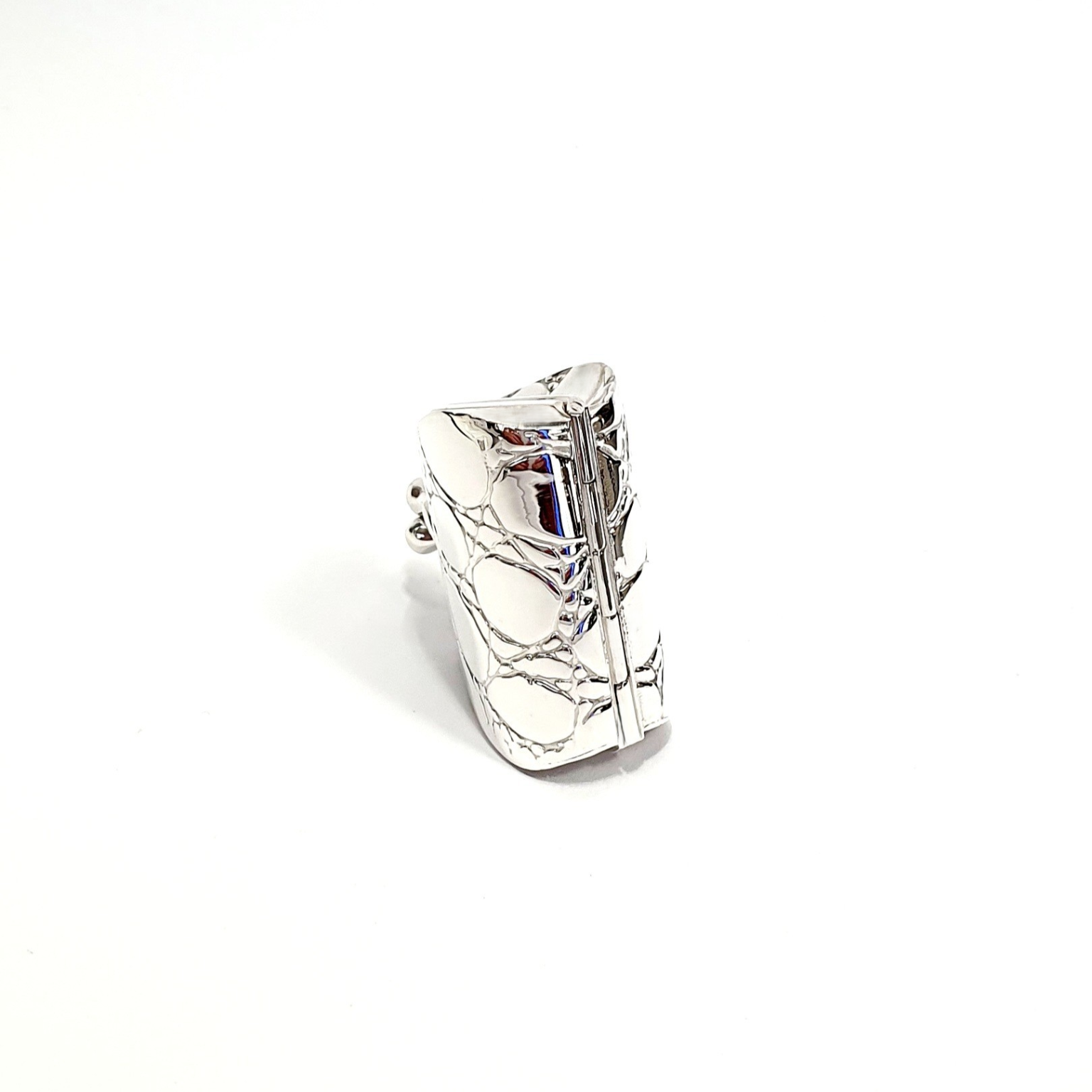 Sterling silver handbag pill box standing upright to display its hinged bottom, highlighting craftsmanship and secure closure detailing.