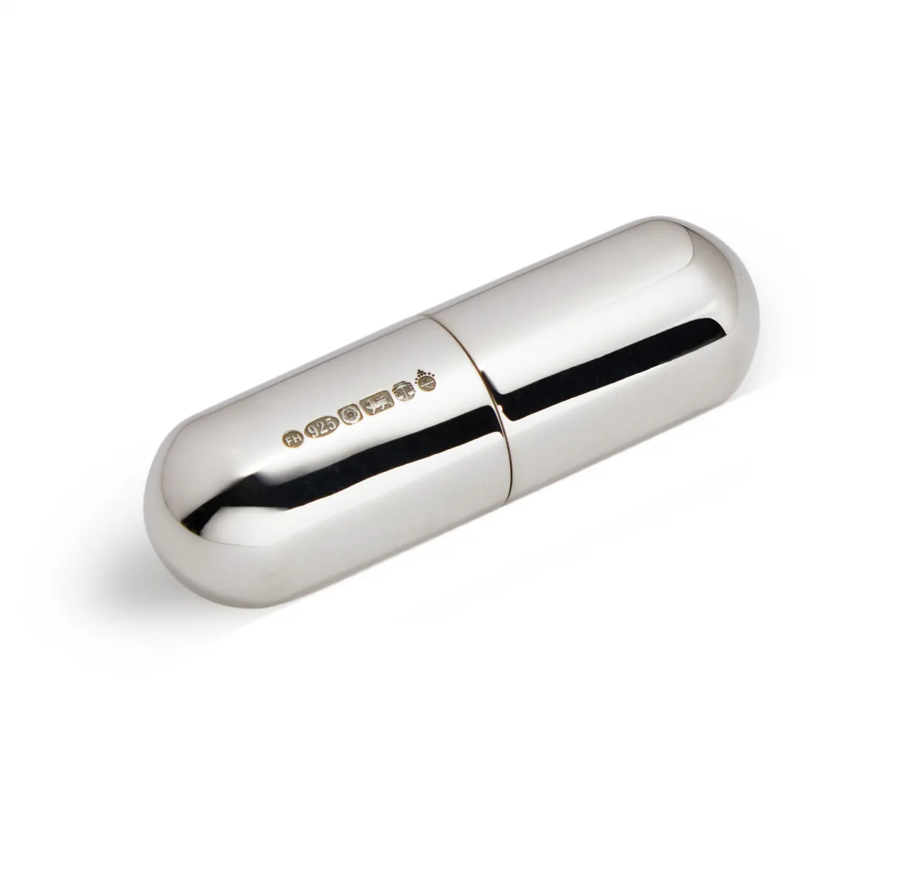 A compact silver pill box in capsule form was photographed against a soft white background, showing the hallmark.