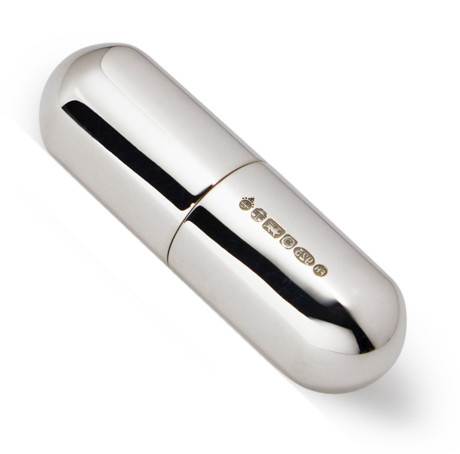 A compact silver pill box in capsule form was photographed against a soft white background, showing the hallmark.