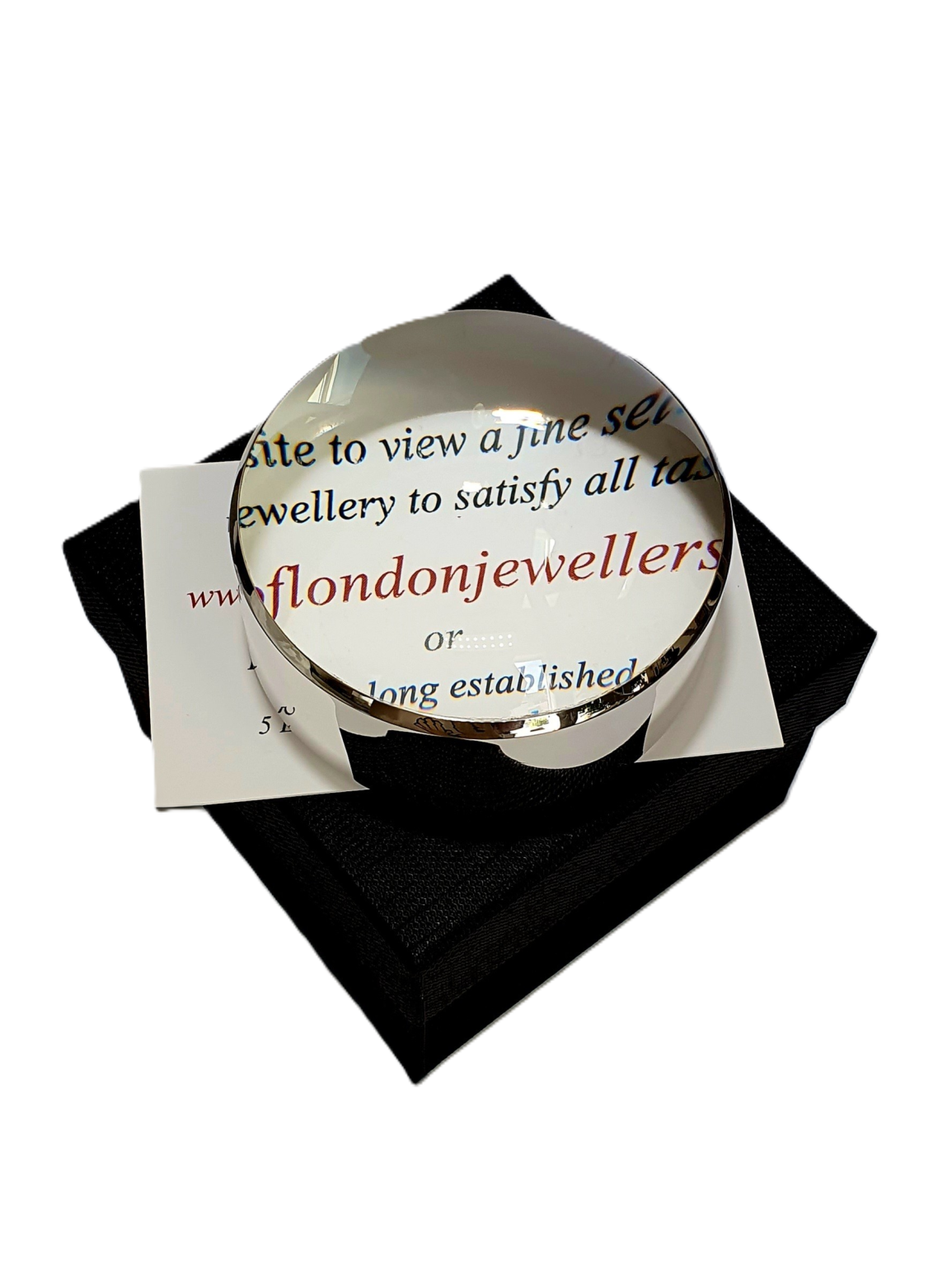 Dual-purpose luxury sterling silver desktop domed paperweight magnifying glass showing the ten times magnification on top of a business card