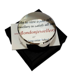 Dual-purpose luxury sterling silver desktop domed paperweight magnifying glass showing the ten times magnification on top of a business card