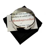 Dual-purpose luxury sterling silver desktop domed paperweight magnifying glass showing the ten times magnification on top of a business card