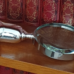 Close-up of sterling silver magnifying glass handle, angled on bookshelf with red leather-bound books in background.8