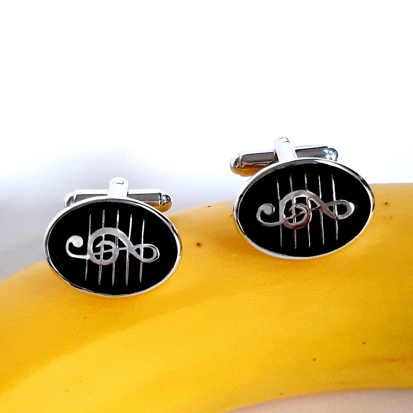 Cufflinks resting on top of a ripe banana highlighting contrast and curvature