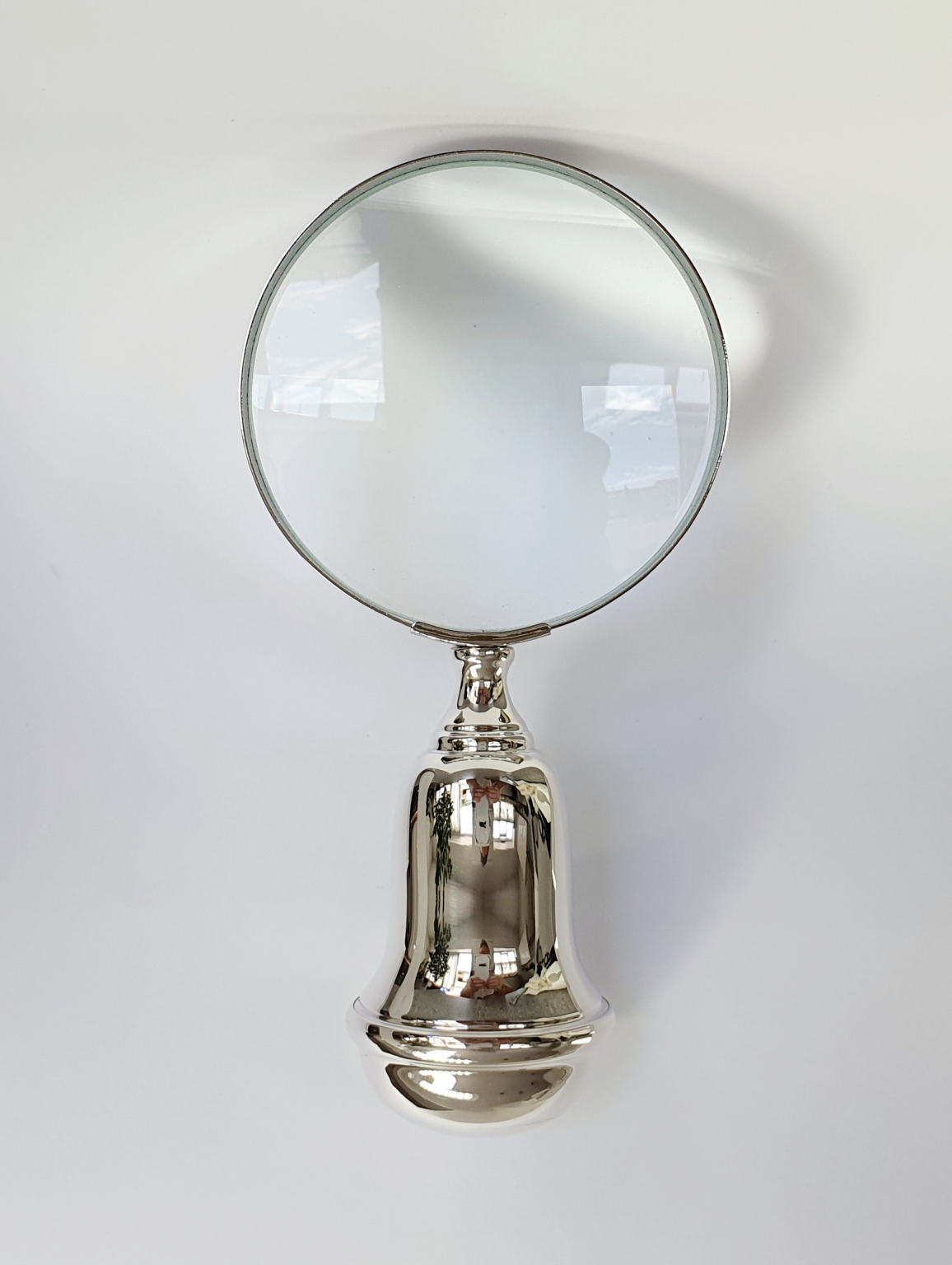 Front-facing magnifying glass against a neutral grey backdrop, showcasing its circular lens and polished silver rim with crisp clarity.