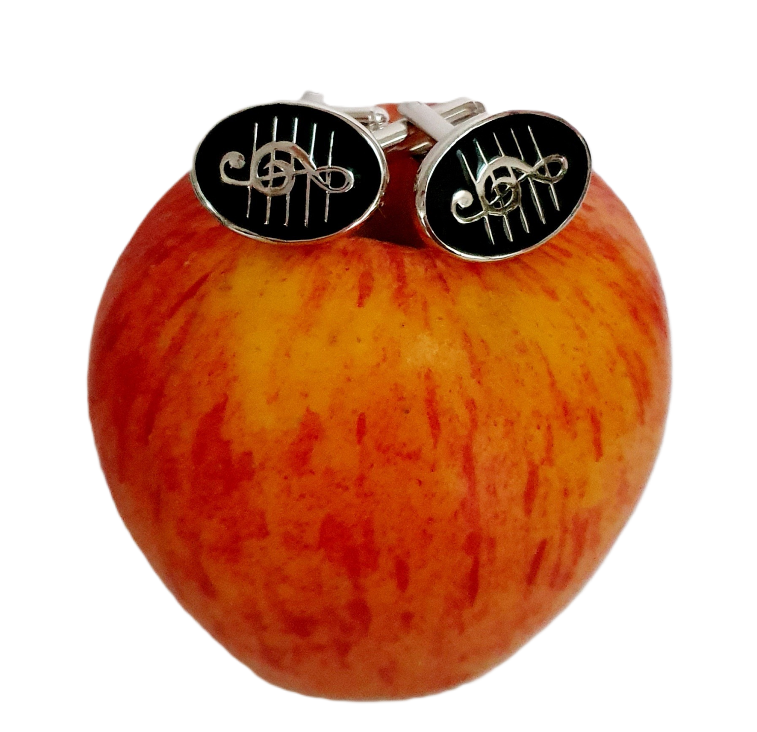 Black enamel Treble Clef cufflinks styled on a red apple, emphasizing polish and musical elegance