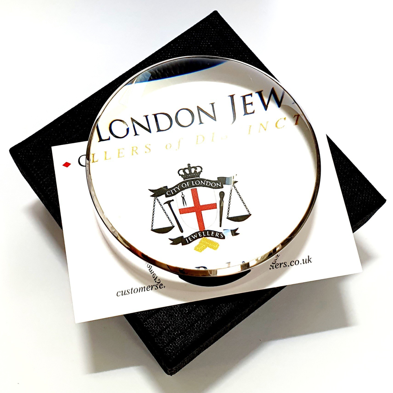 Dual-purpose luxury sterling silver desktop domed paperweight magnifying glass showing the ten times magnification on top of a business card