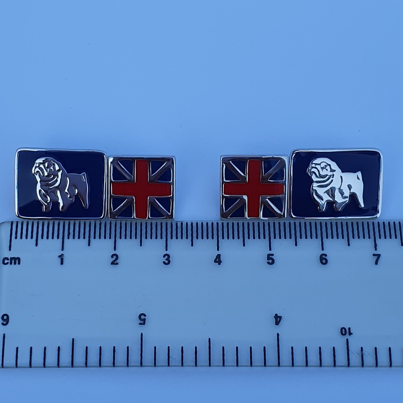Sterling silver Union Jack and Bulldog cufflink placed on a ruler to show size and scale.