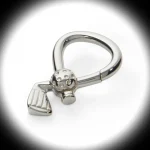 Genuine silver golf club and ball key ring is presented on a white background with a soft black‑shaded spotlight effect. The left‑facing angle emphasizes the club’s elegant curve and the textured ball detail.