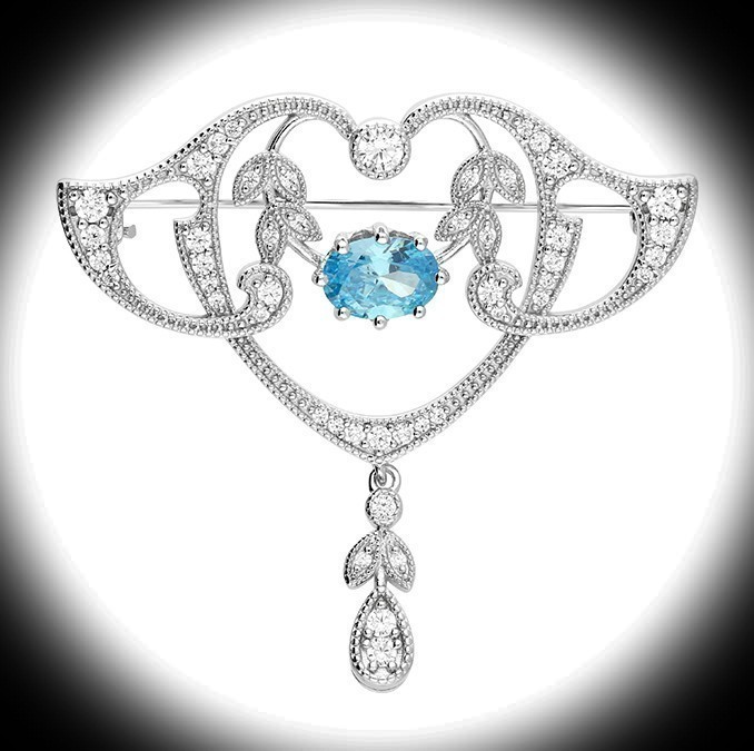 Sterling Silver Art Nouveau Style Brooch with blue and white stones displayed against a black surround with a white spotlight highlighting the centre of the brooch.