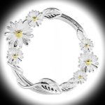 A dramatic black‑background image of the Sterling Silver Daisy Circle Brooch illuminated by a soft white spotlight at the centre. The two‑tone daisies glow warmly, while the wrapped stem and polished silver circle create a striking contrast.