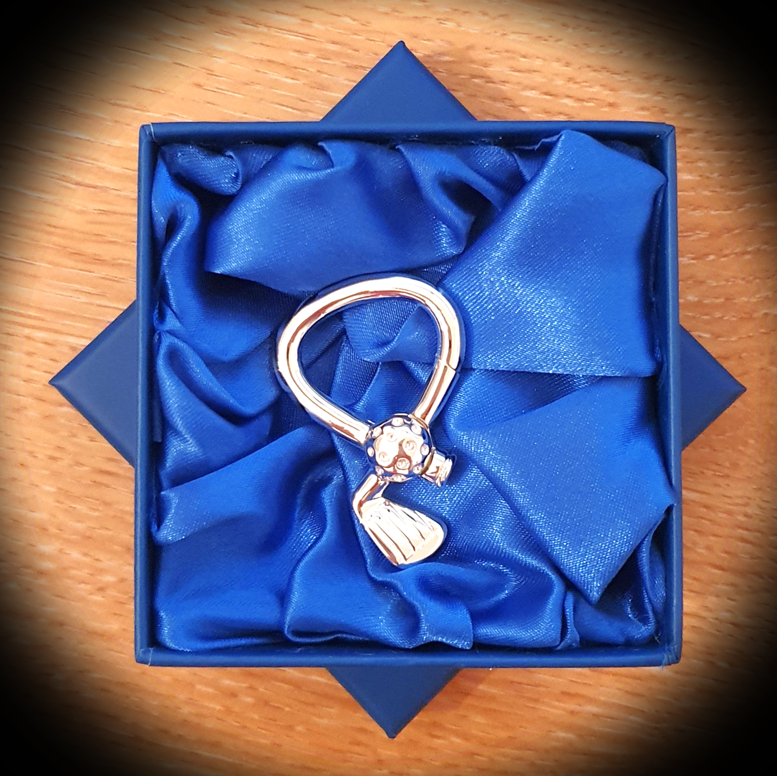 A Hallmarked silver golfing key fob presented in a blue gift box with smooth blue silk lining, The contrast between the deep blue tones and the polished silver creates an elegant, gift‑ready display.