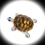 Close‑up of a single sterling silver tortoise cufflink with vitreous enamel shell and sapphire eye, shown on a black background with a soft white spotlight effect highlighting the details.