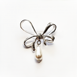 A stunning bow-shaped brooch on a white background, emphasizing its detailed craftsmanship and central teardrop pearl.