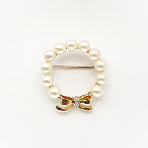 A 9ct yellow gold brooch with a circle of eleven 5mm round pearls leading to a bow to the bottom with three petite round diamonds set to the centre of the bow. Front view showing the pin threw the centre.