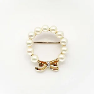 A 9ct yellow gold brooch with a circle of eleven 5mm round pearls leading to a bow to the bottom with three petite round diamonds set to the centre of the bow. Front view showing the pin threw the centre.